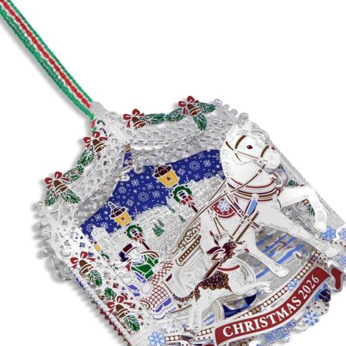Newbridge Silverware 2026 dated Christmas tree decoration showing an intricate 3D silver-plated winter scene with a horse-drawn sleigh, a bounding dog, snowy streets, and colorful enamel accents with a green and red hanging ribbon.